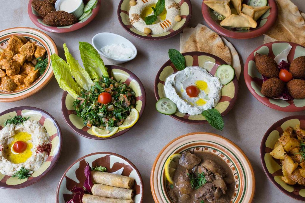 Assortiment généreux de mezzés levantins servis dans plusieurs assiettes traditionnelles